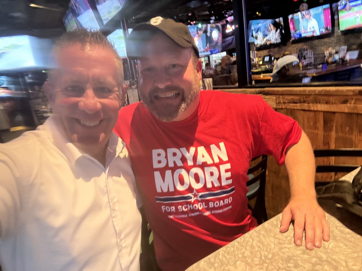 Bryan Moore, in a white shirt, seated beside a supporter wearing a Bryan Moore for School Board T-shirt.